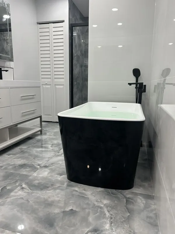 Gray bathroom with a black freestanding tub, white vanity, and stone-look floor