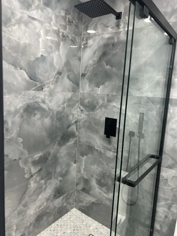 Glass shower enclosure with charcoal gray stone-look walls and a recessed shower floor
