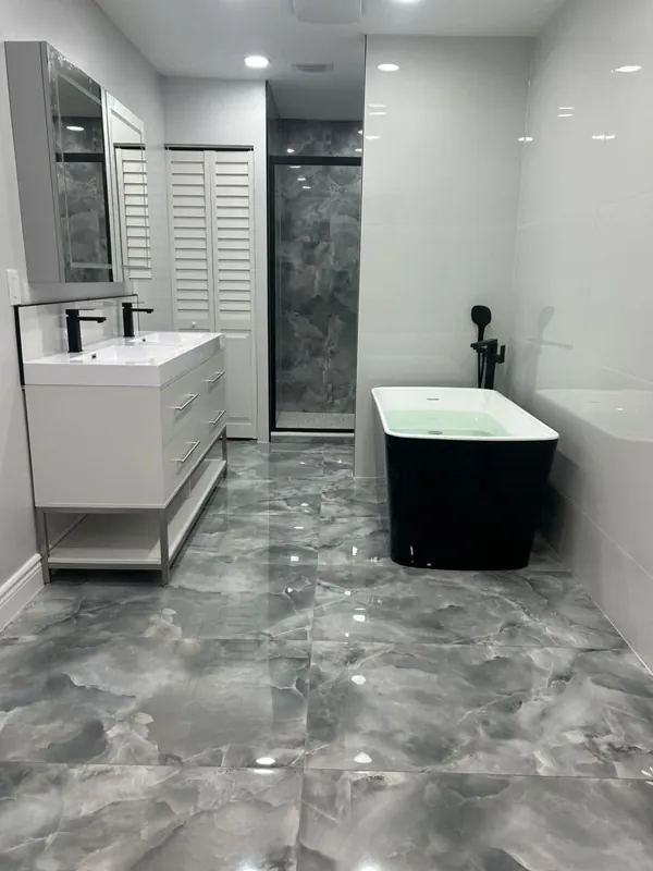 Wide view of a gray bathroom showing the dark tub, vanity, and dark wall finish