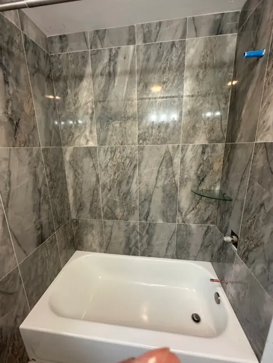 Gray marble-look tub wall with a white tub and dark gray veining