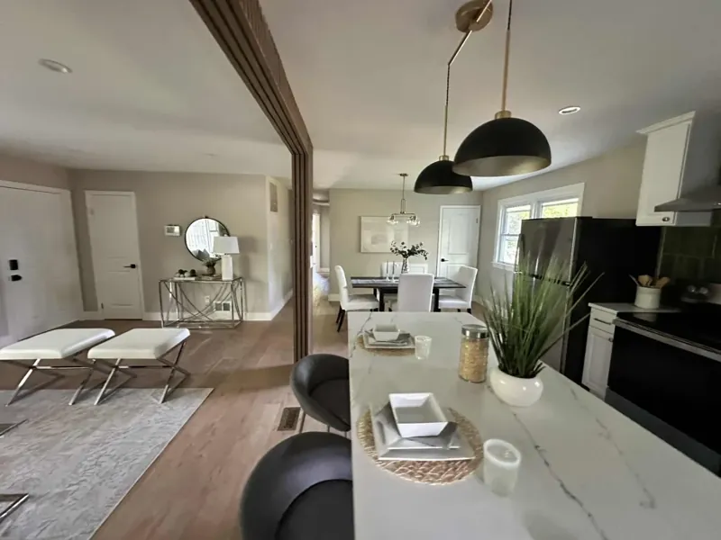 Kitchen and dining view with a medium-brown floor, pendant lights, pale counters, and dark accent cabinetry
